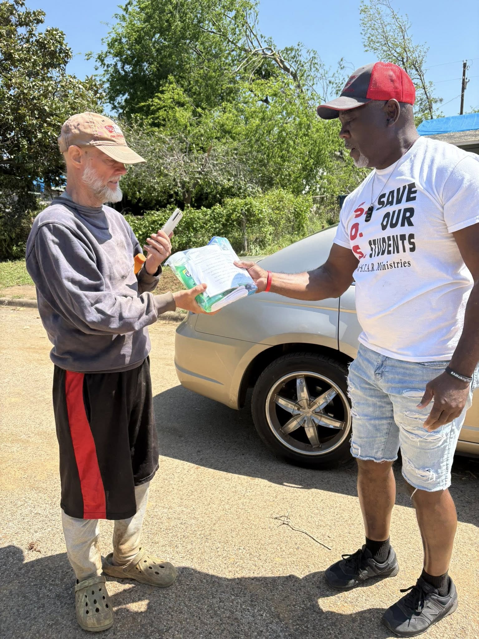 Patrick hands relief supplies to an adult neighbor during the Lone Star tornado relief trip.