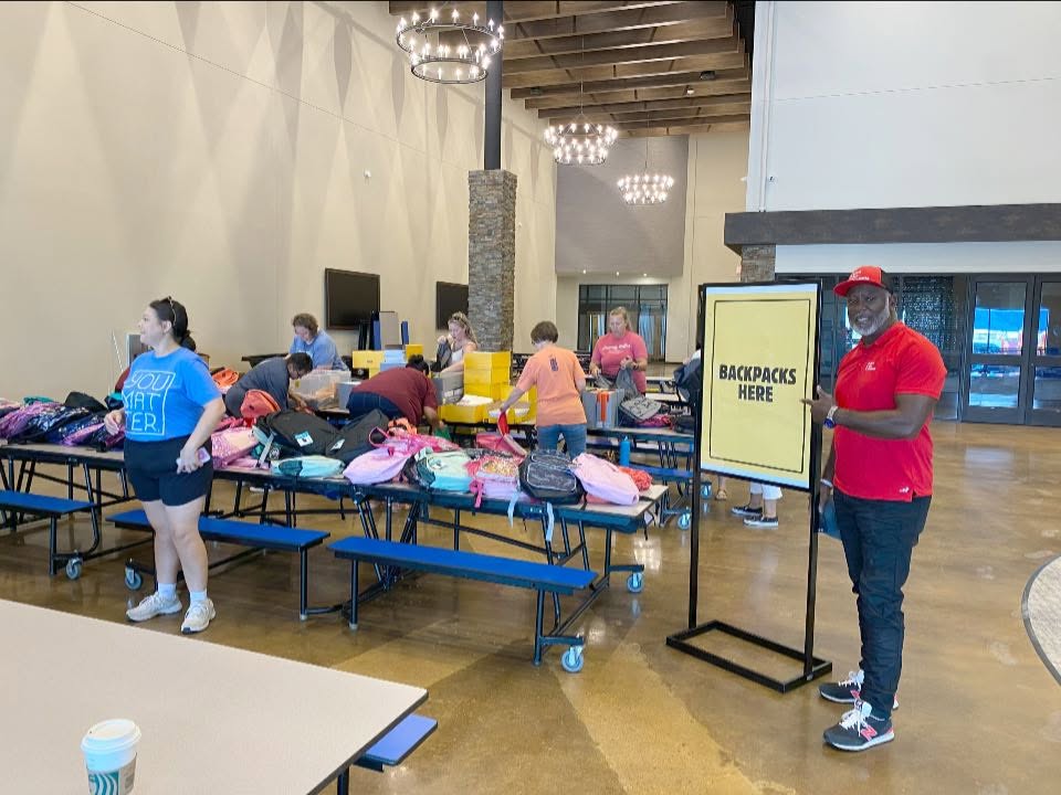 Patrick beside tables of backpacks during his San Angelo school-supply return.