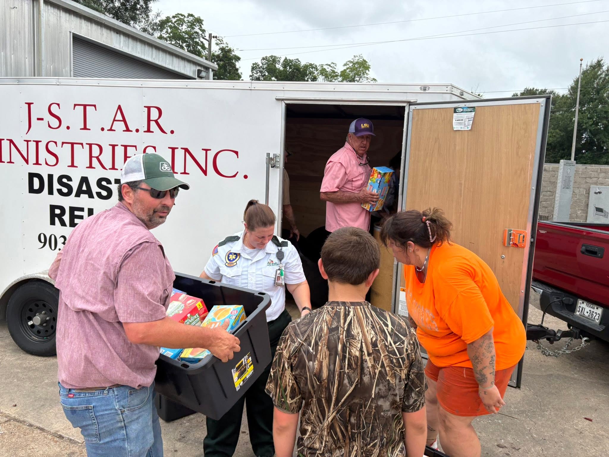 Community helpers unload boxes and bins of donated supplies during Trip #83.
